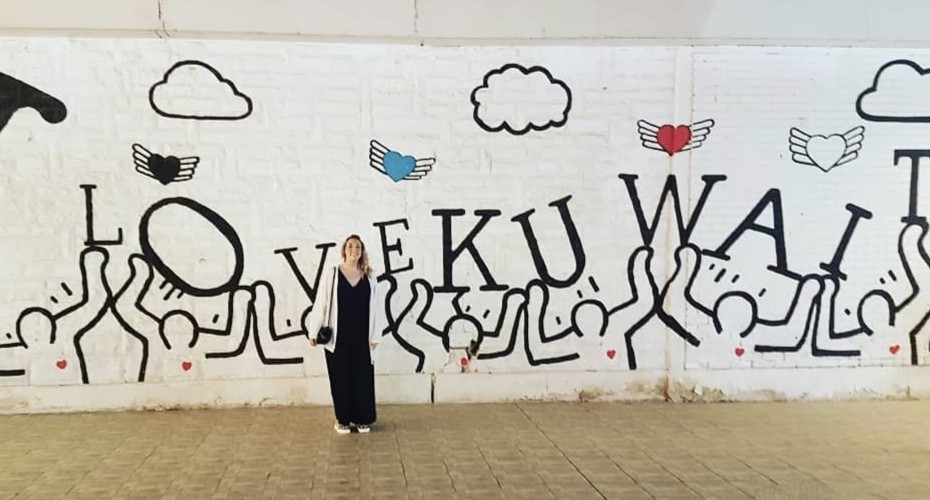 Sally standing in front of a I Love Kuwait mural in the style of Keith Haring