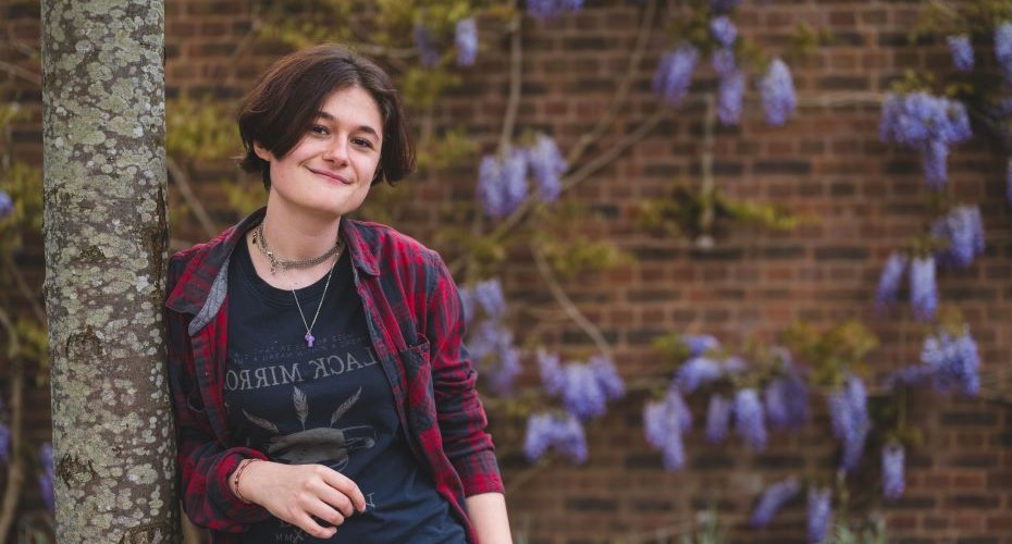 Smiling student in front of a wall with some flowers