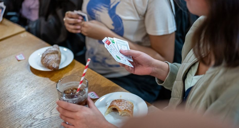 Students playing card games and eating pastries at the Intercultural Cafe