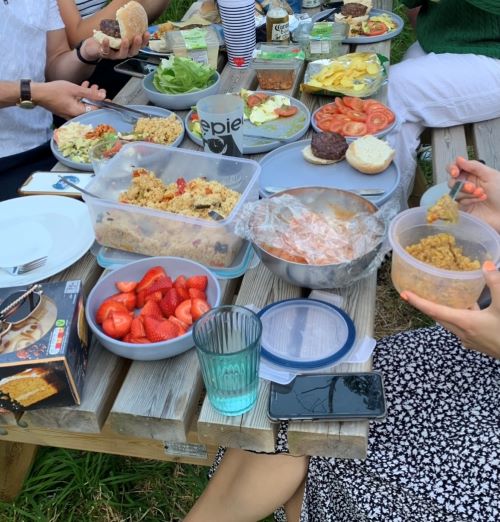 A wooden picnic table covered in BBQ food