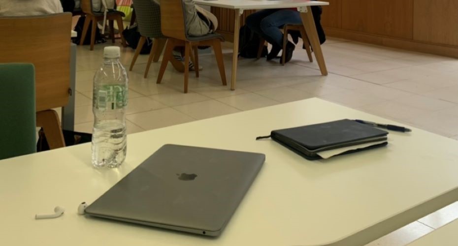 Laptop, notebook and water bottle on a study space desk