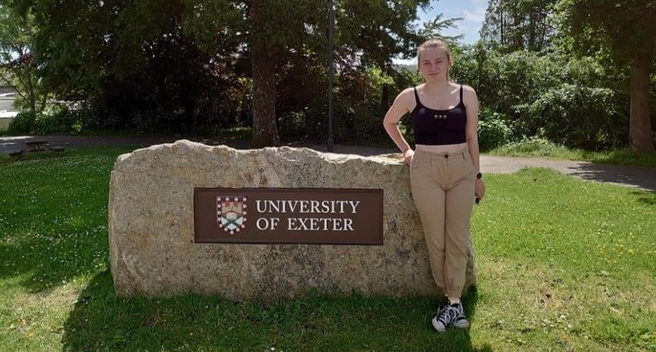 Cerys Deakin (4th year MSci Zoology student) stood next to the University Exeter rock on the Penryn campus.