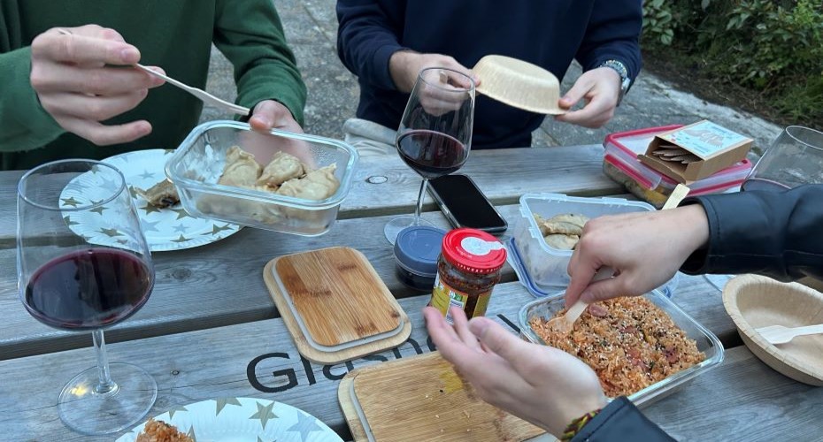 Friends enjoying red wine and Asian food at a picnic bench