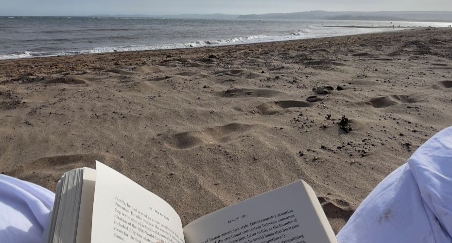 View of an open book on a sandy beach looking towards the beach
