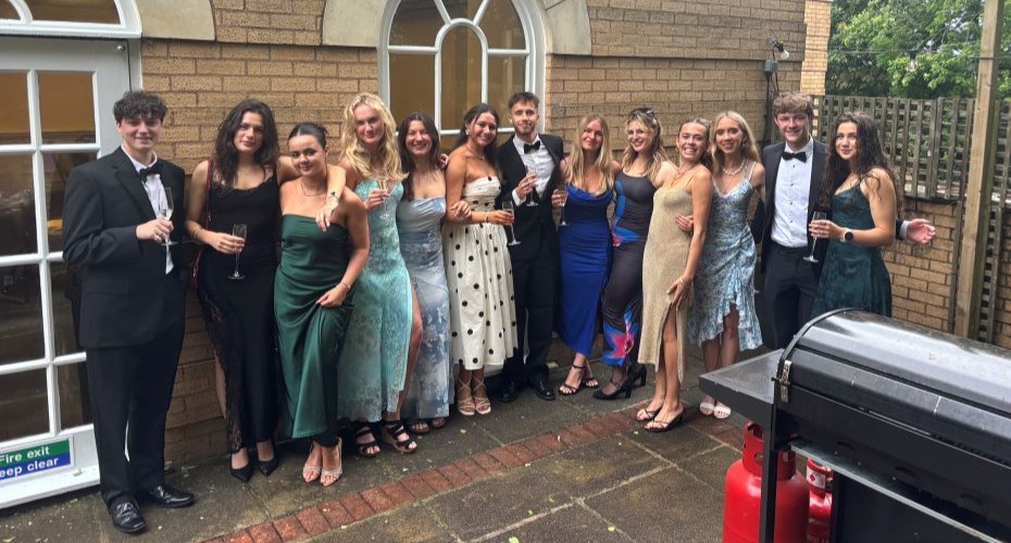 Large group of students in formal dress standing in a line smiling at the camera