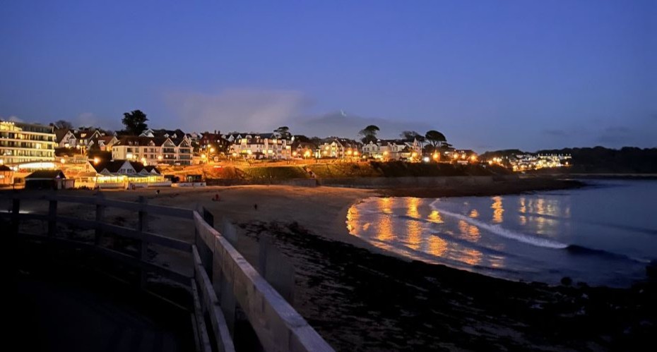 View of brightly lit buildings along the coast in the evening