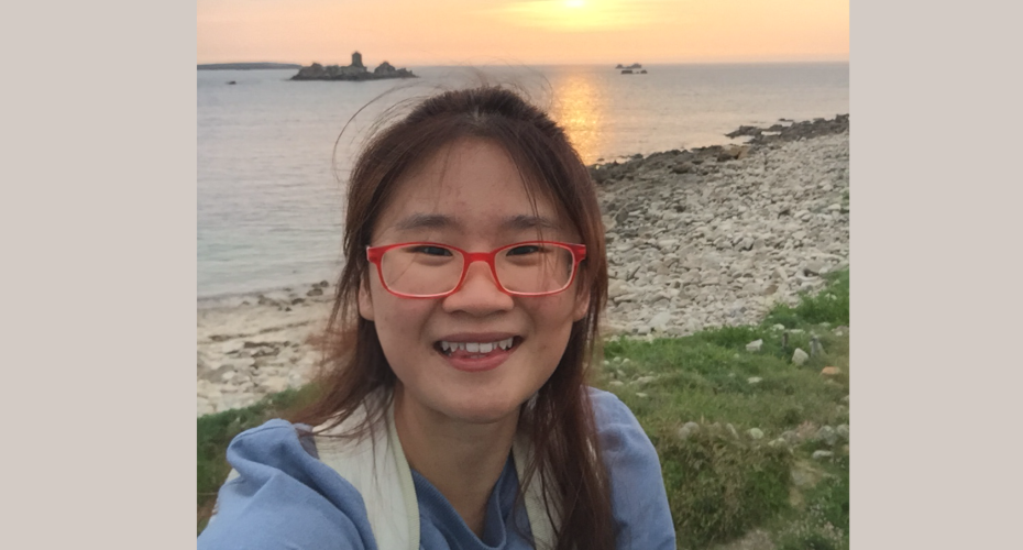 photo of Cheryl standing by the seaside with a sunset behind