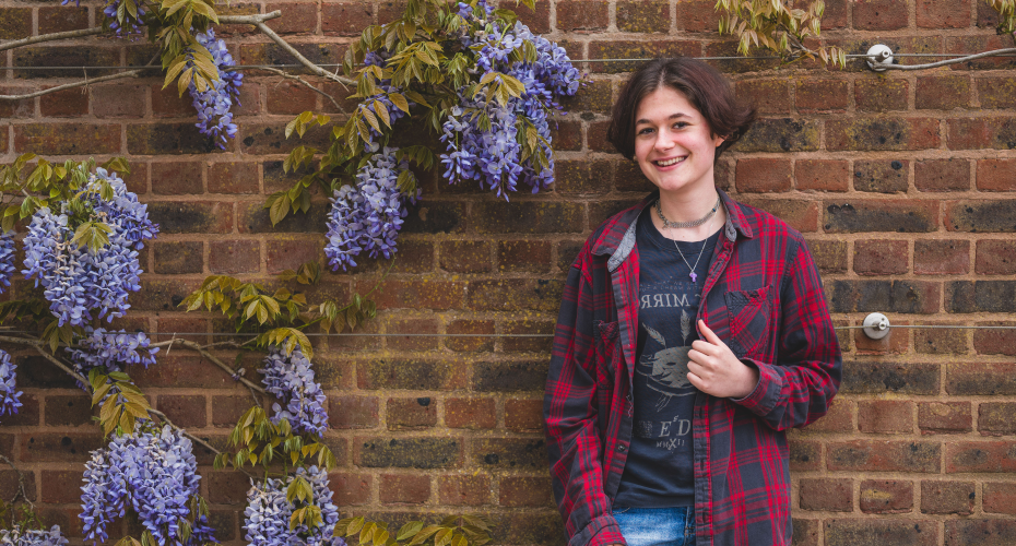 Eleanor standing in front of wall with wisteria