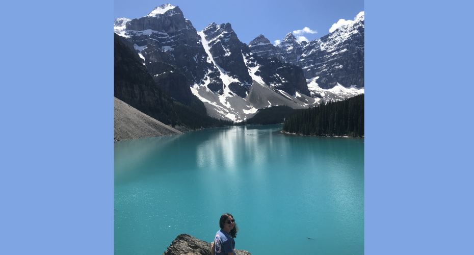 Ellie on a cliff with a turquoise lake and snow capped mountains